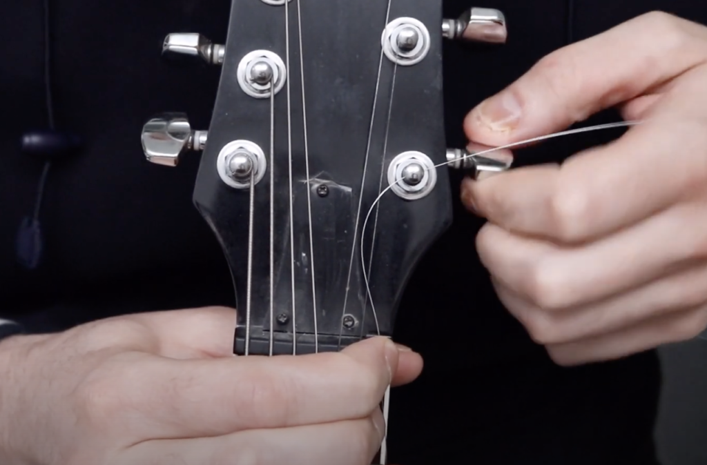 Comment changer ses cordes de guitare par D. WEX Music : maintenir correctement sa corde lorsque l'on tourne la mécanique.